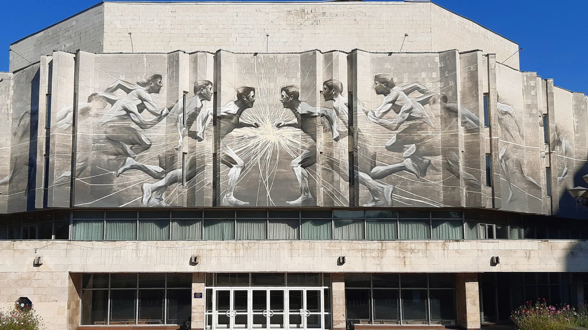 Mural detail on a Kyiv Polytechnic Institute building: figures reaching towards a radiant central form.